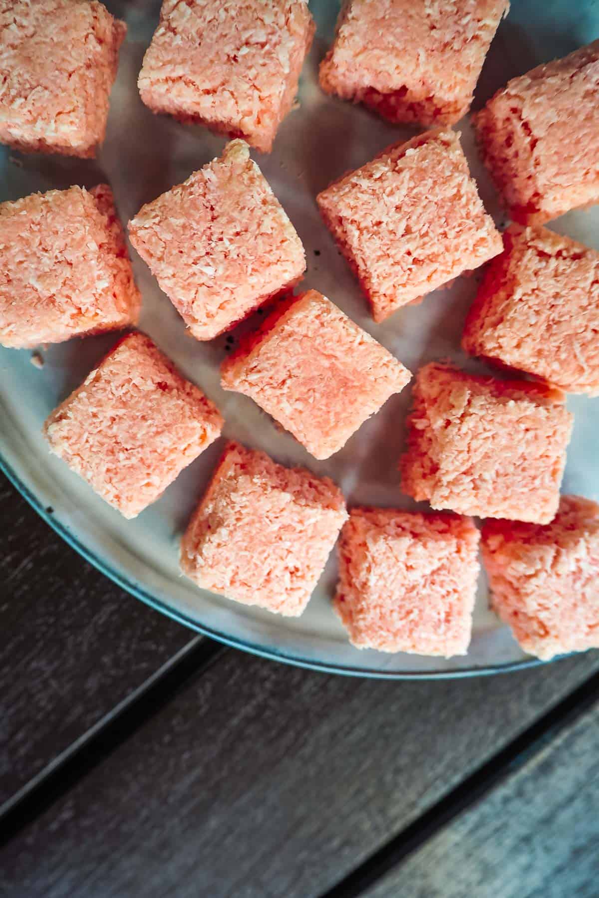 Blocks of coconut candy in pink on a white plate