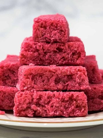 Pink bars of coconut candy stacked on a plate.