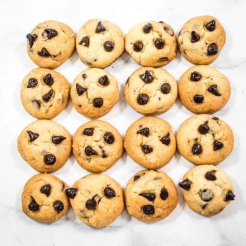 Four rows of chocolate chips cookies against a marble background.