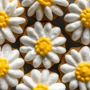 Round cookies decorated with royal icing piped daisies.