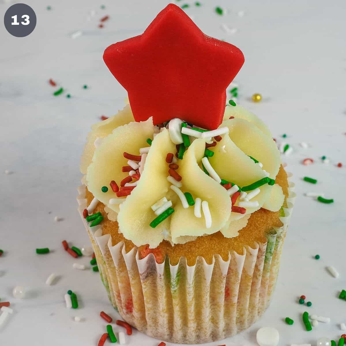 A cupcake with red star topper and sprinkles.