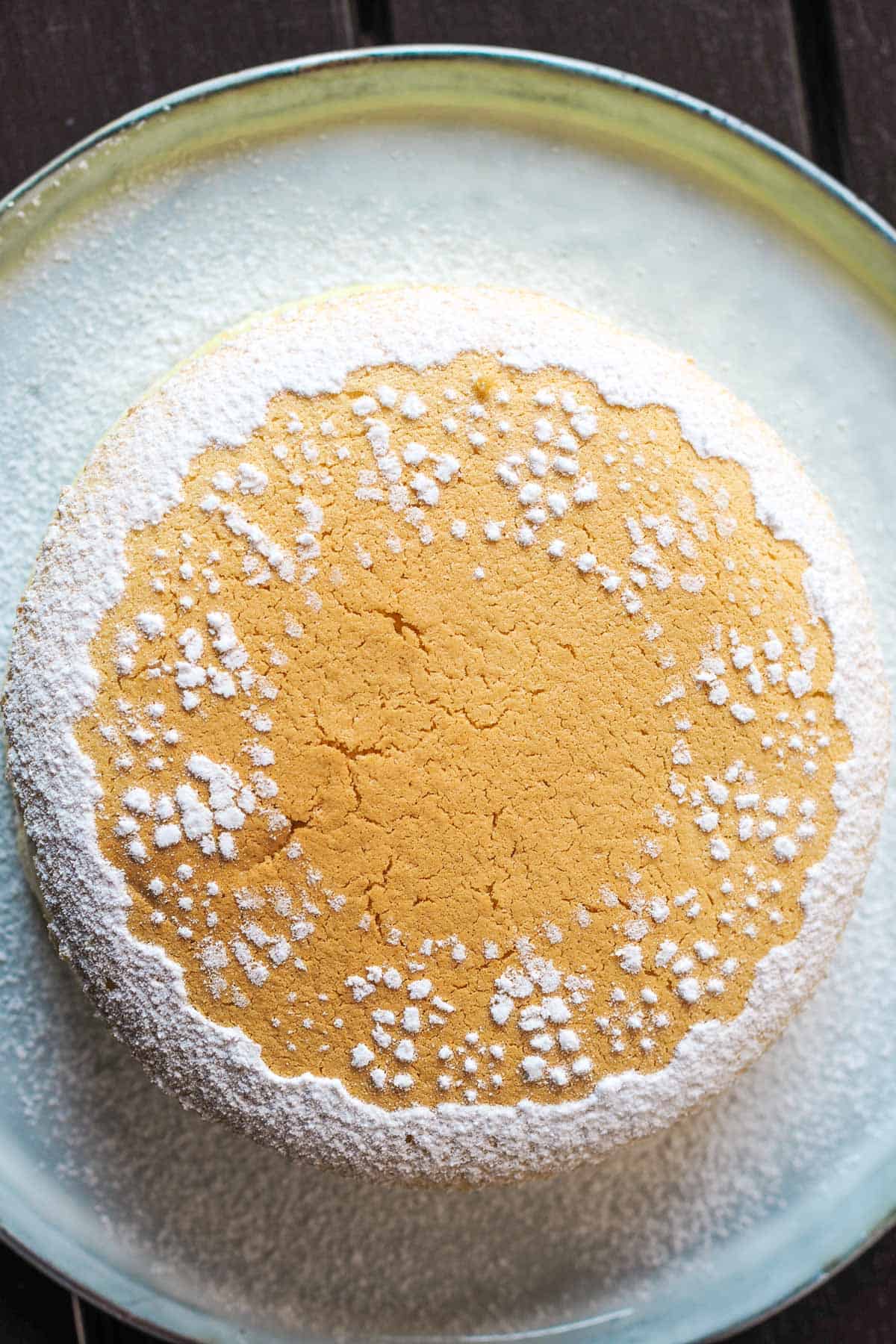 A round cake decorated with icing sugar lace dredge
