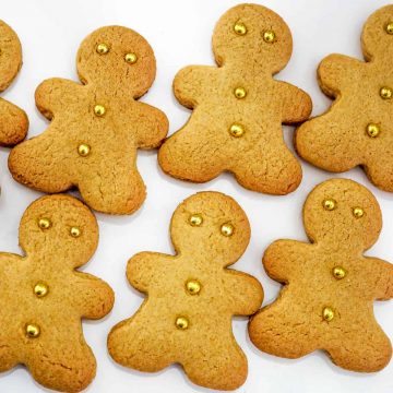 Gingerbread cookies cut into gingerbread men shapes and decorated with gold dragees.