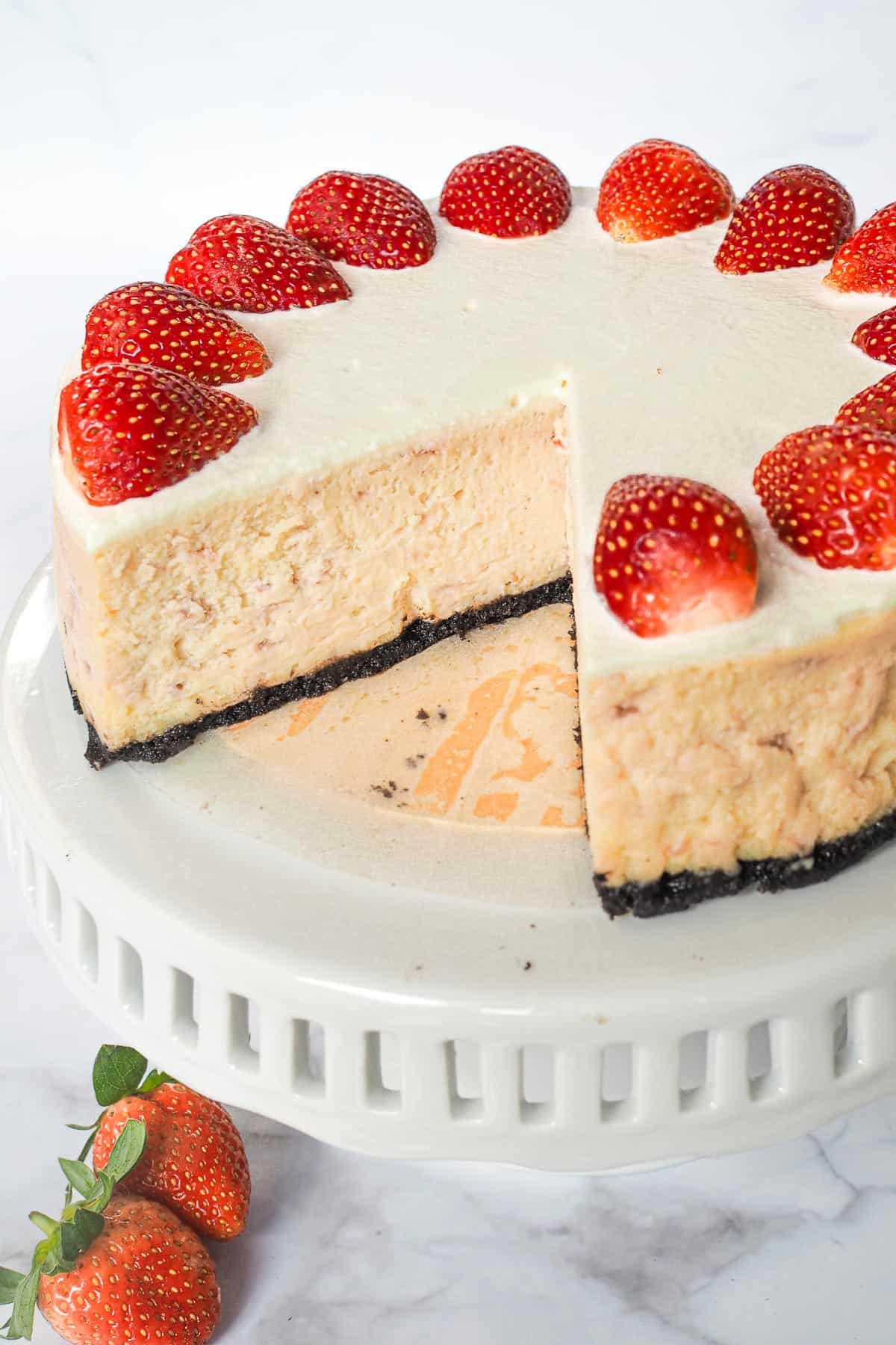 A round strawberry cheesecake with a slice cut out.