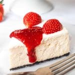 A slice of Oreo strawberry cheesecake with strawberry topping and fresh strawberries.