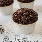 Chocolate cupcake with chocolate buttercream in white cupcake casings. Cupcakes are topped with gold and chocolate sprinkles