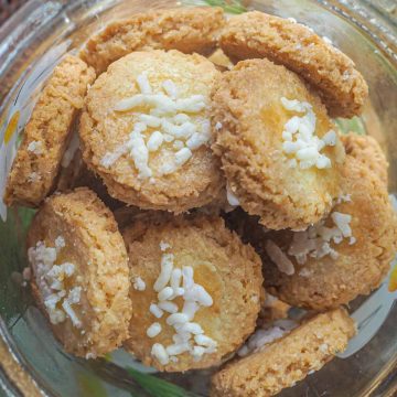 Close up of crispy coconut cookies with white sprinkles topping in a jar
