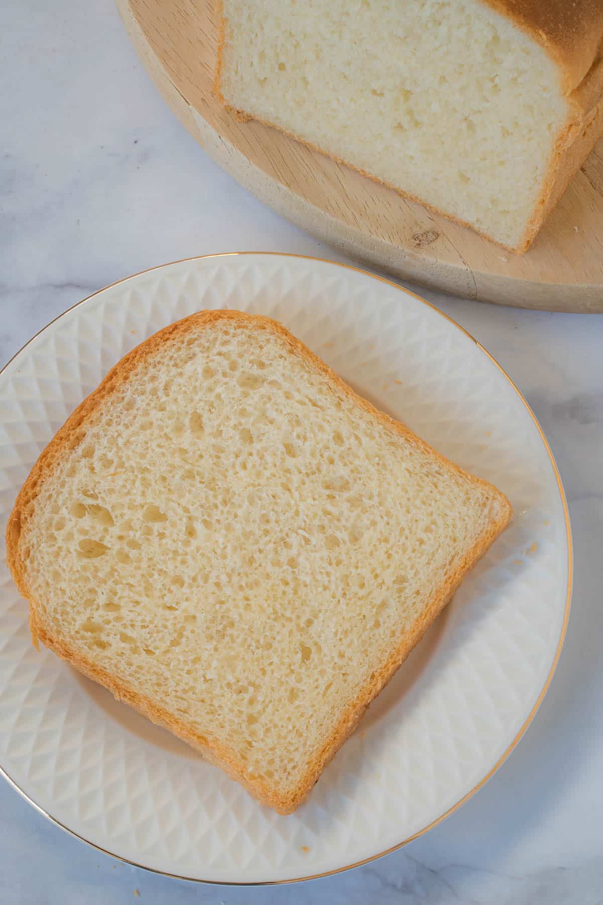 A slice of plain white bread on a white plate.