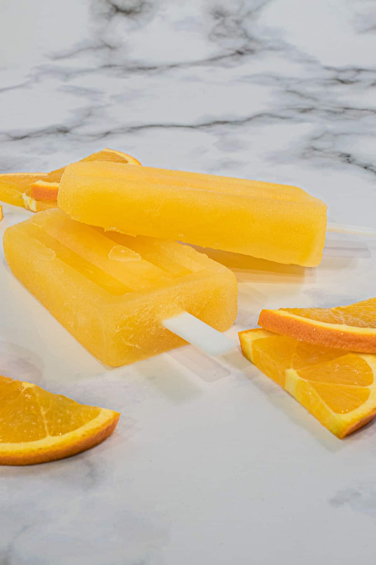 2 orange ice pop on one another, against a marble background
