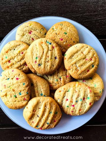 Round cookies with sprinkles on a white plate.