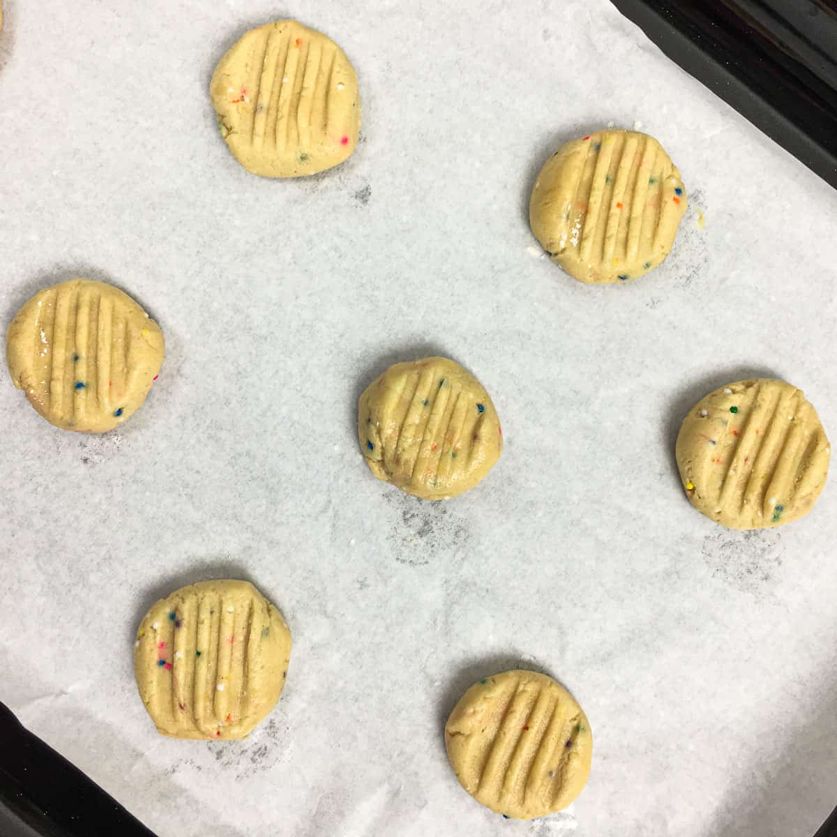 Round unbaked cookies on a parchment paper.