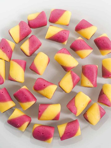 Pink and yellow butter mint candy arranged in a circular motion on a white plate