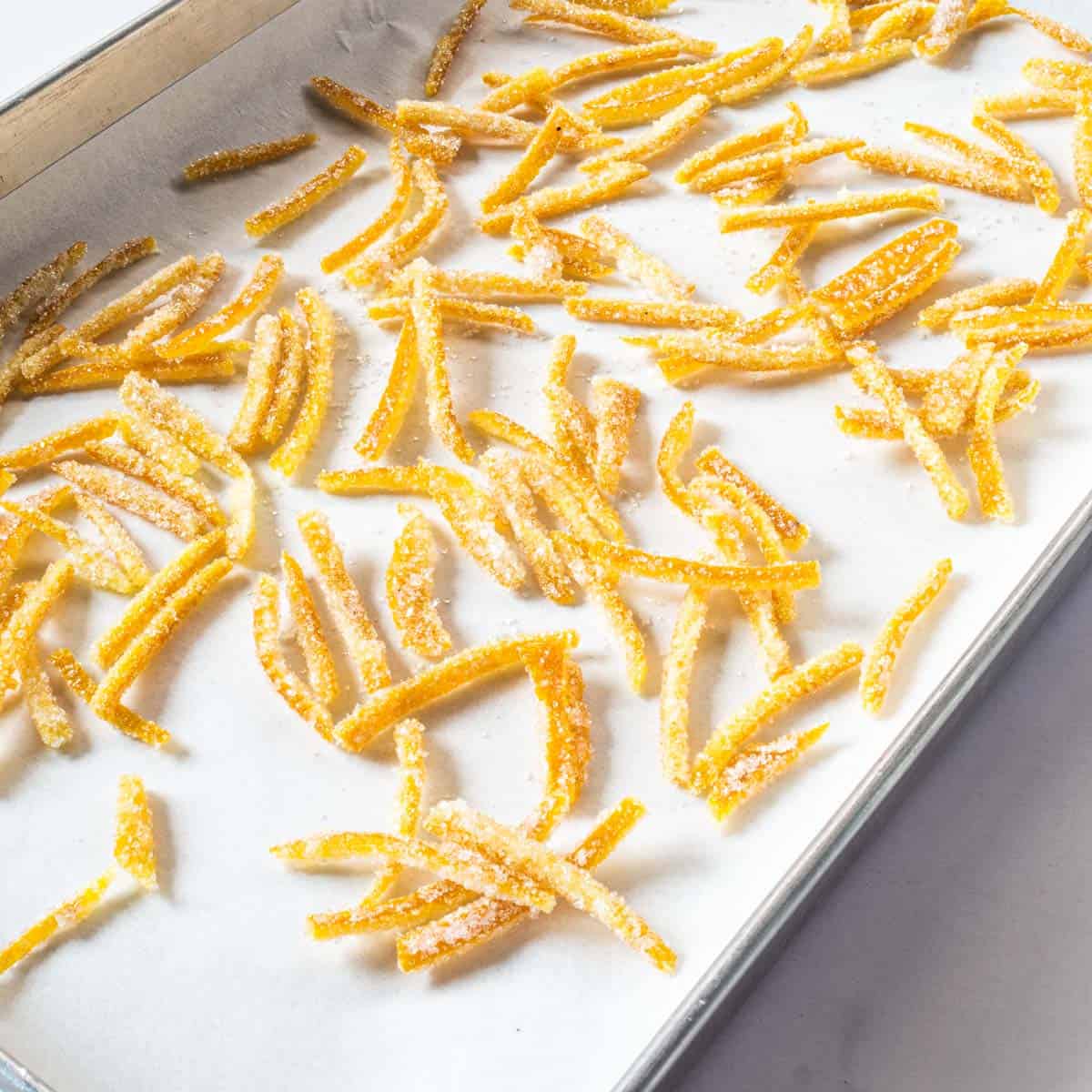 Orange peel candy on a parchment lined rectangle tray.