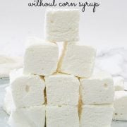 A bunch of square marshmallows stacked up on a white plate.