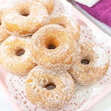 A tray of sugar coated ring doughnuts.