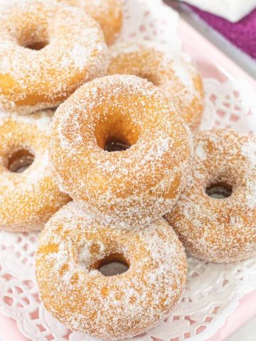 A tray of sugar coated ring doughnuts.