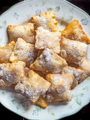 Fried square pastry puffs on a floral plate.