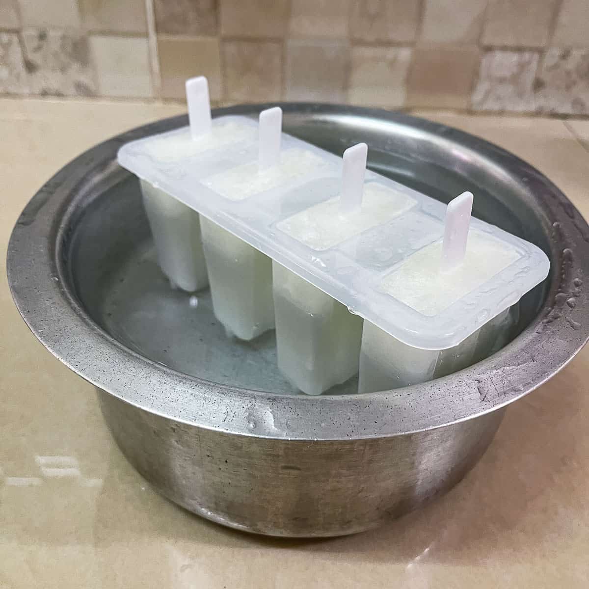A popsicle mold in a pot of water