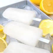 3 lemon popsicles on a tray of ice cubes and slices of lemons