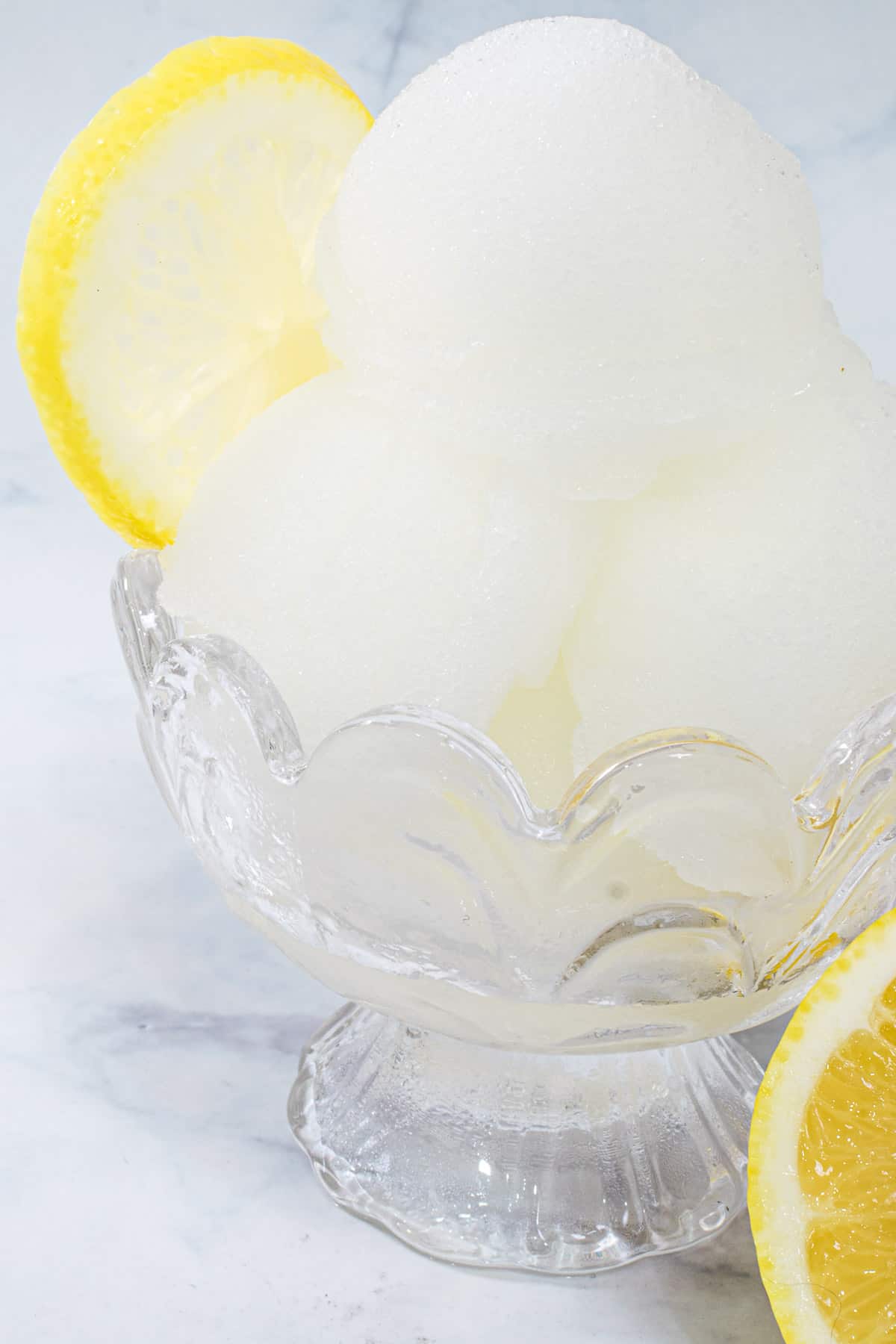 Lemonade sorbet in a dessert cup, with lemon on the side
