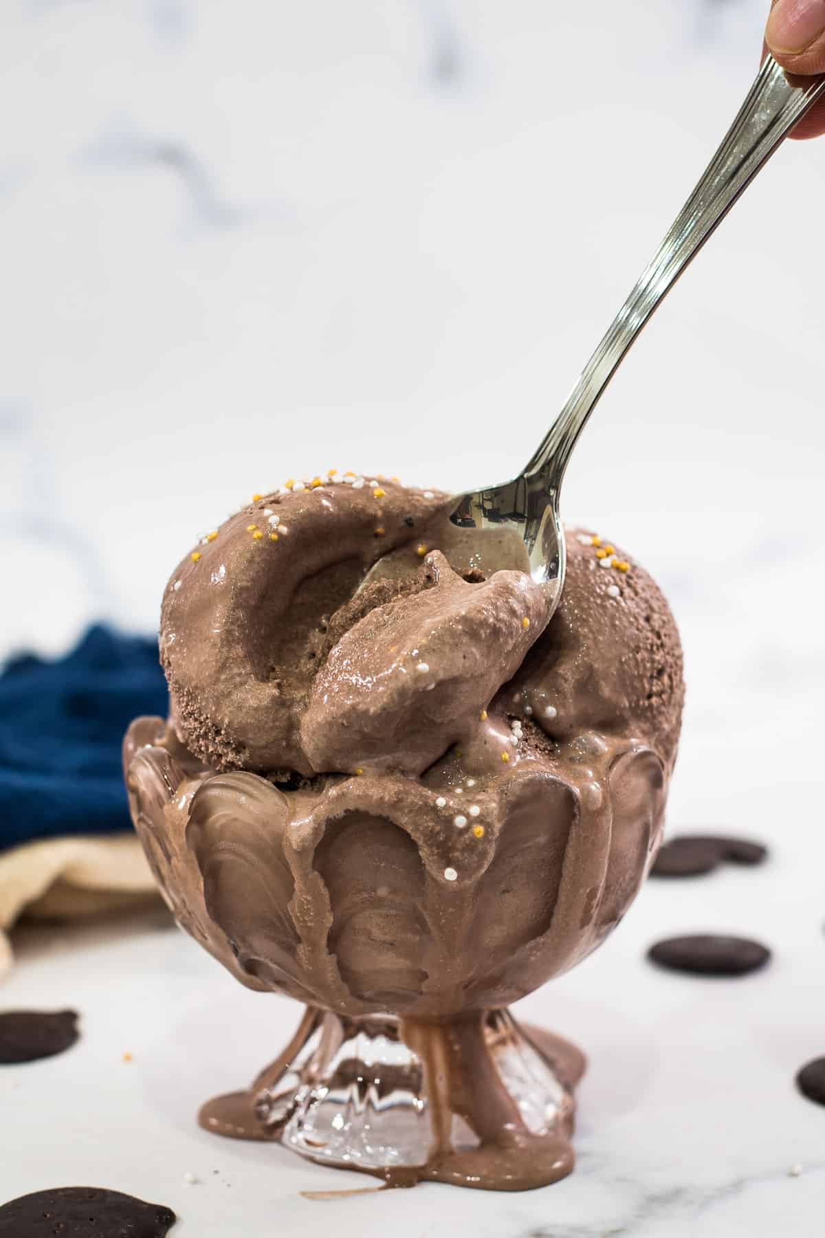 Using a spoon to scoop out chocolate ice cream from a dessert bowl