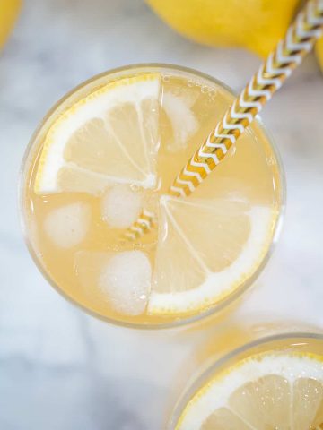 Top view of a lemon drink with quartered lemon slices and ice cubes in it.