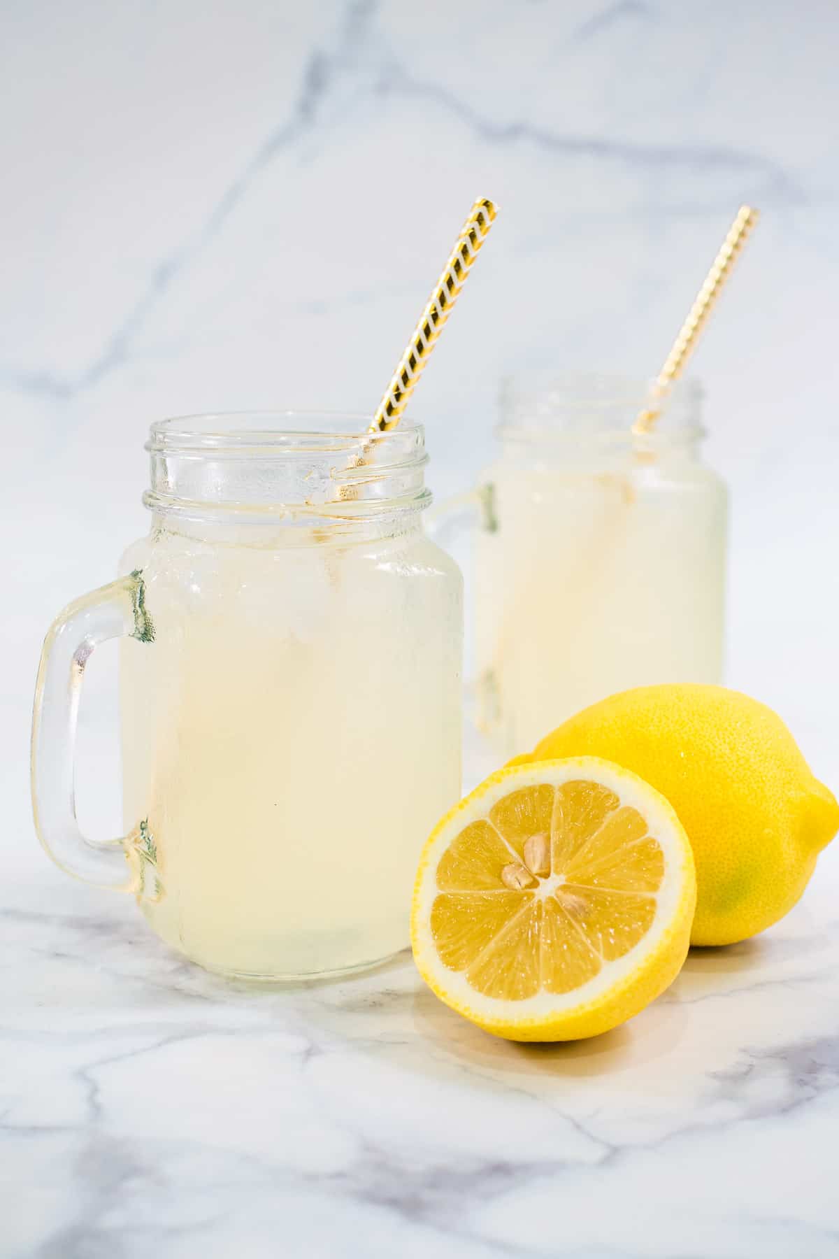 2 glasses of lemonade with straw it them.