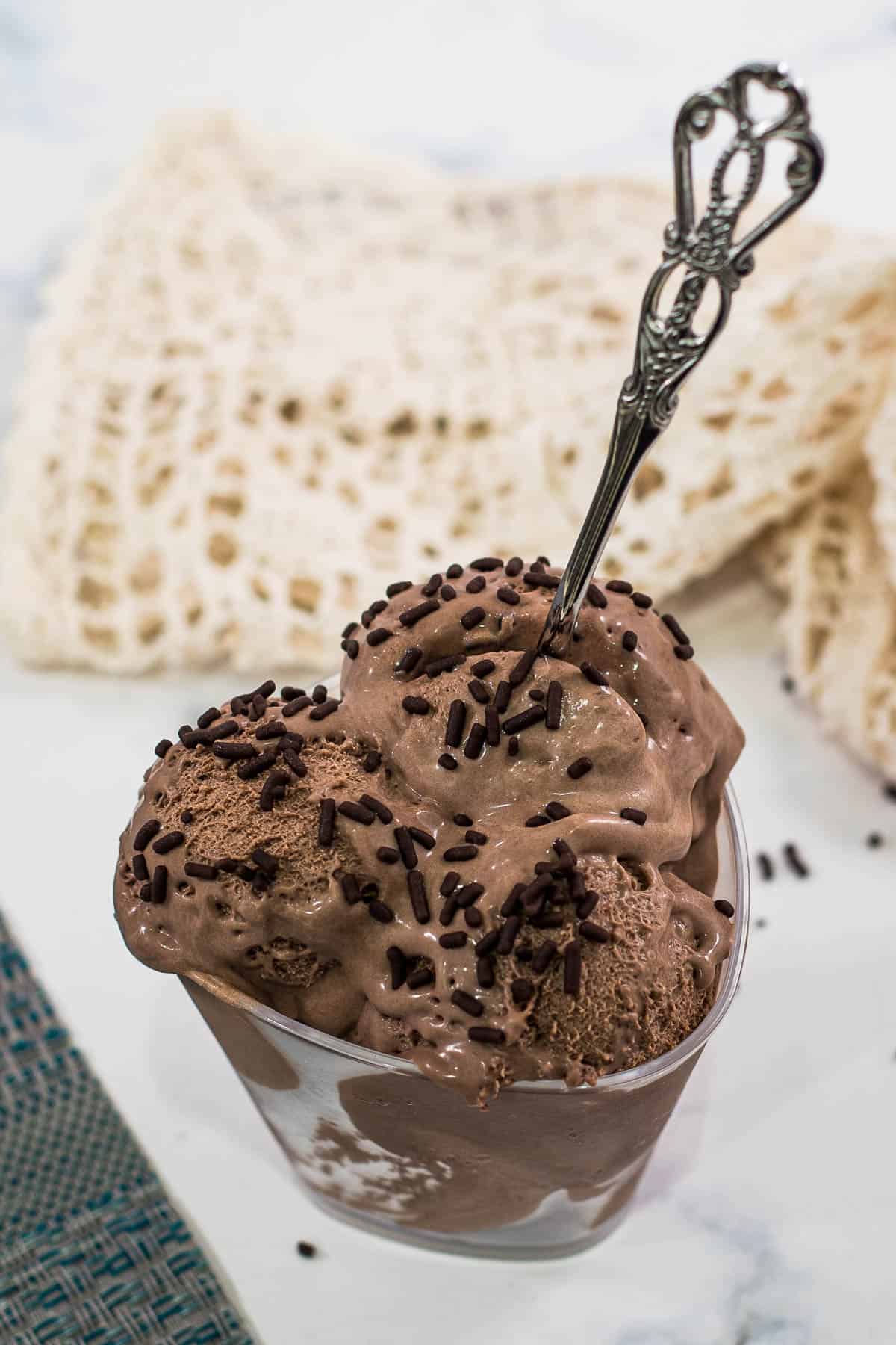 A spoon put into a dessert bowl filled with chocolate ice cream