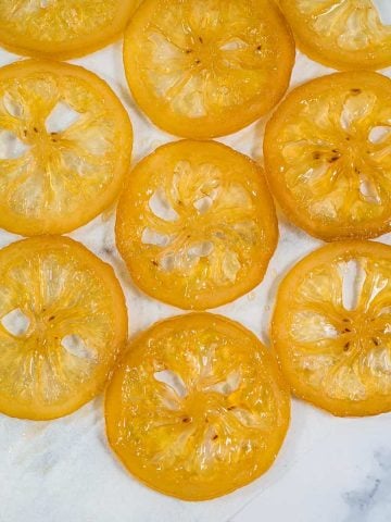 Close up of candied lemon slices against a marble background.