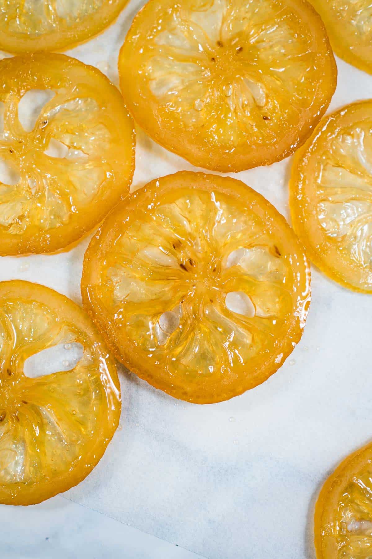 Close up of candied lemon slices against a marble background.