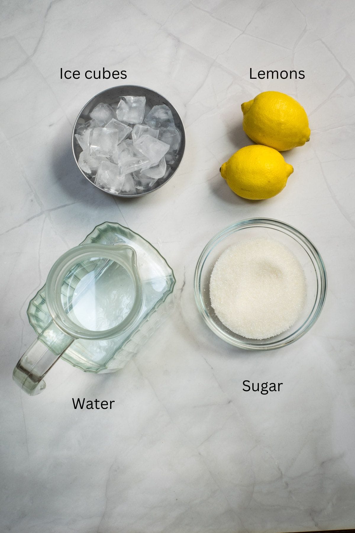 Ice cubes, lemons, sugar and water against a marble background.