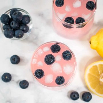 Top view of pink lemonade with blueberries in two glasses.
