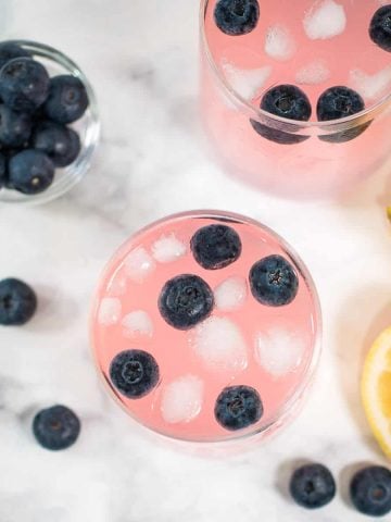 Top view of pink lemonade with blueberries in two glasses.