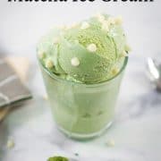 A small glass of green ice cream with while chocolate chips