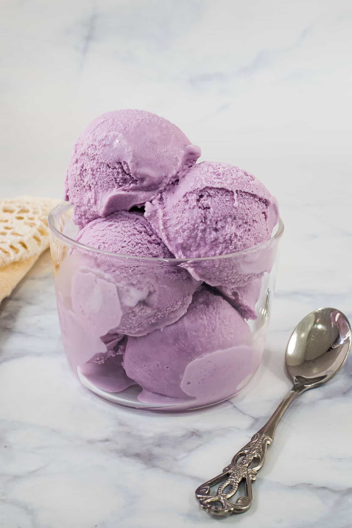 Scoops of purple ube ice cream in a transparent glass
