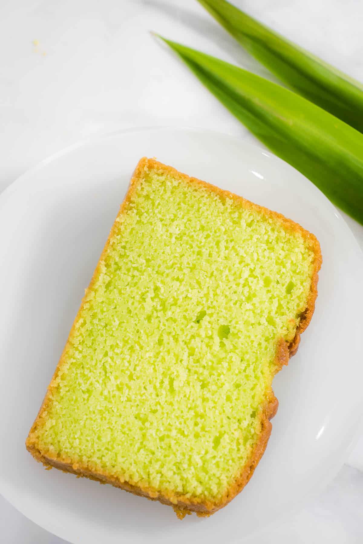 A slice of green pandan loaf cake on a white place