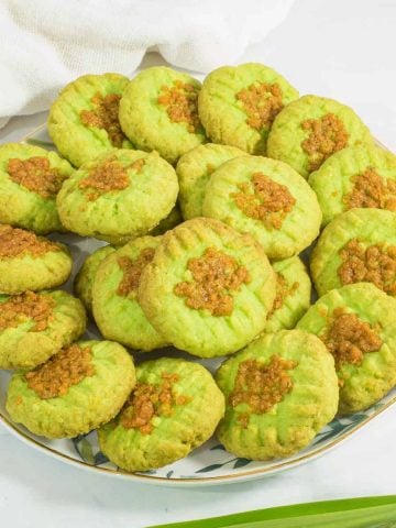A plate of green pandan cookies against a marble background.