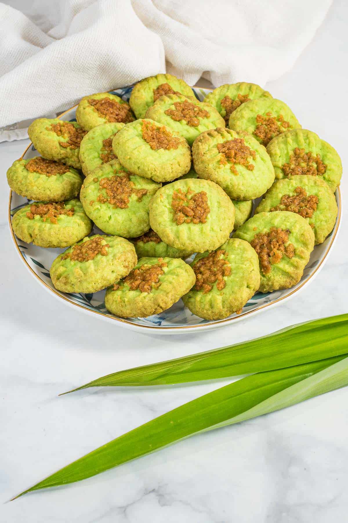 A plate of green pandan cookies against a marble background