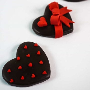 A set of 3 heart shaped cookies decorated with red hearts and bow