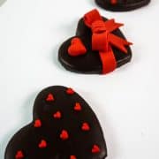 A set of 3 heart shaped cookies decorated with red hearts and bow.