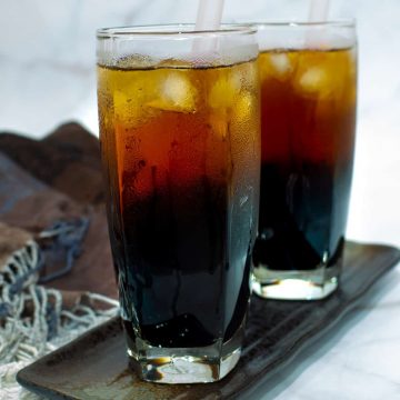 Iced grass jelly tea in 2 tall glasses on a rectangle plate