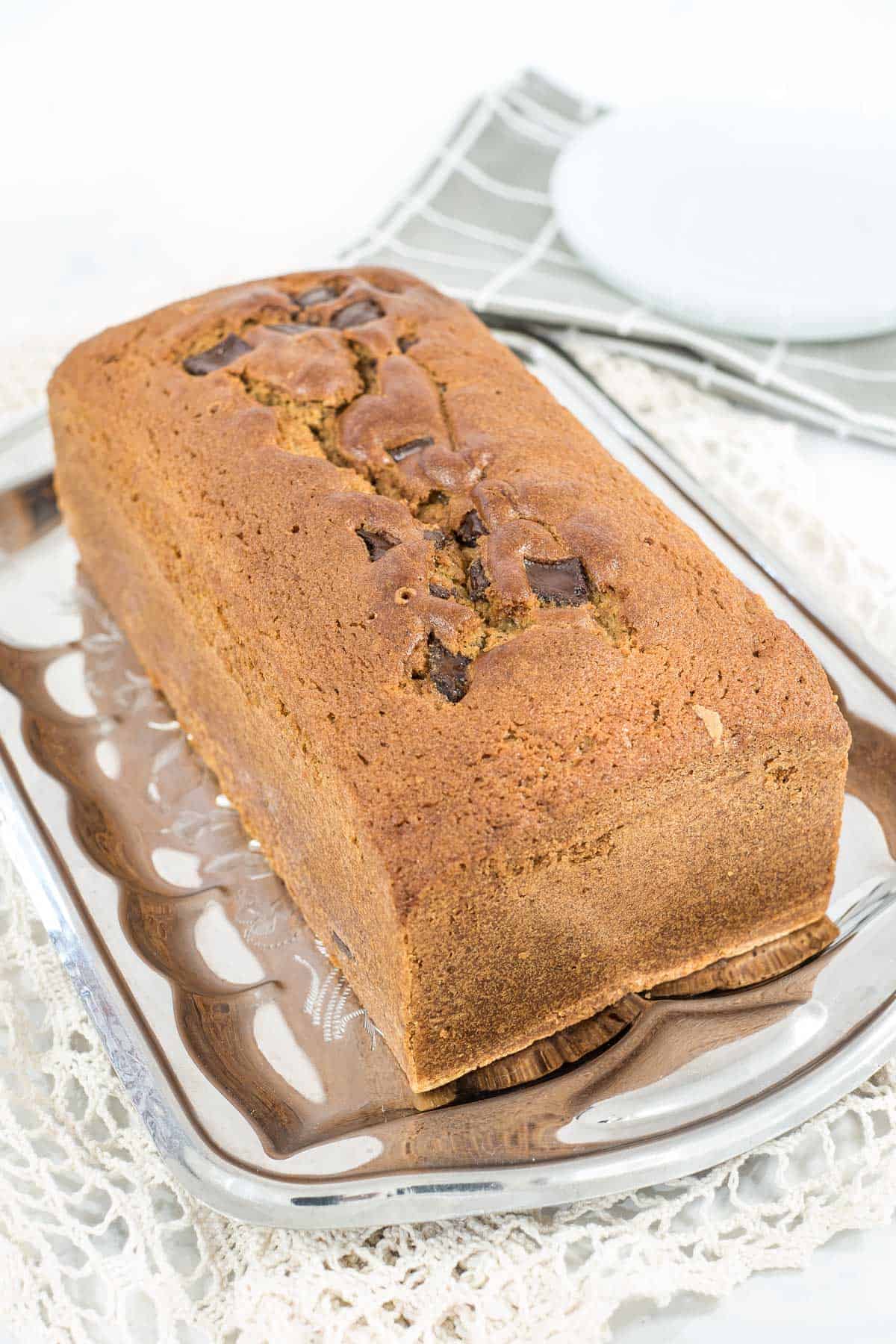 A loaf of cake with chocolate chunks on a silver tray