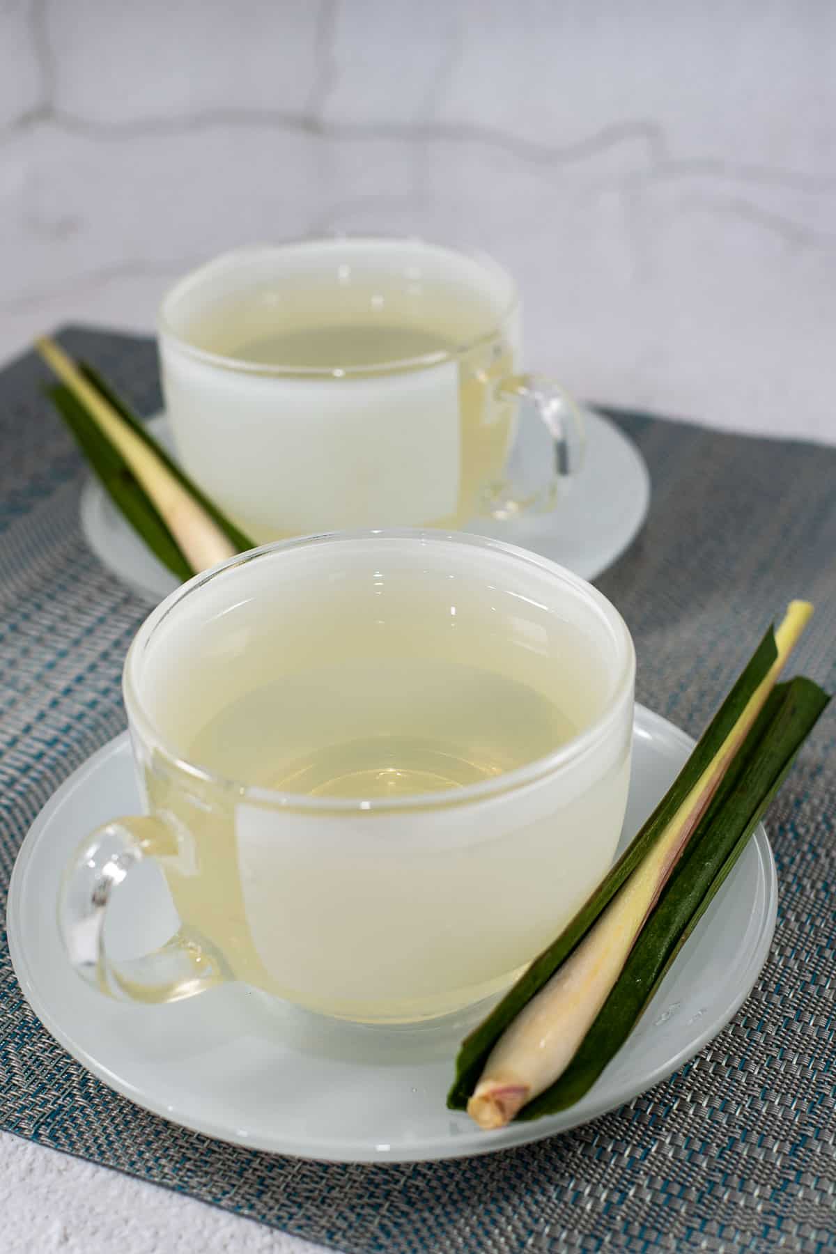 2 cups of drinks with lemongrass and pandan on the saucers