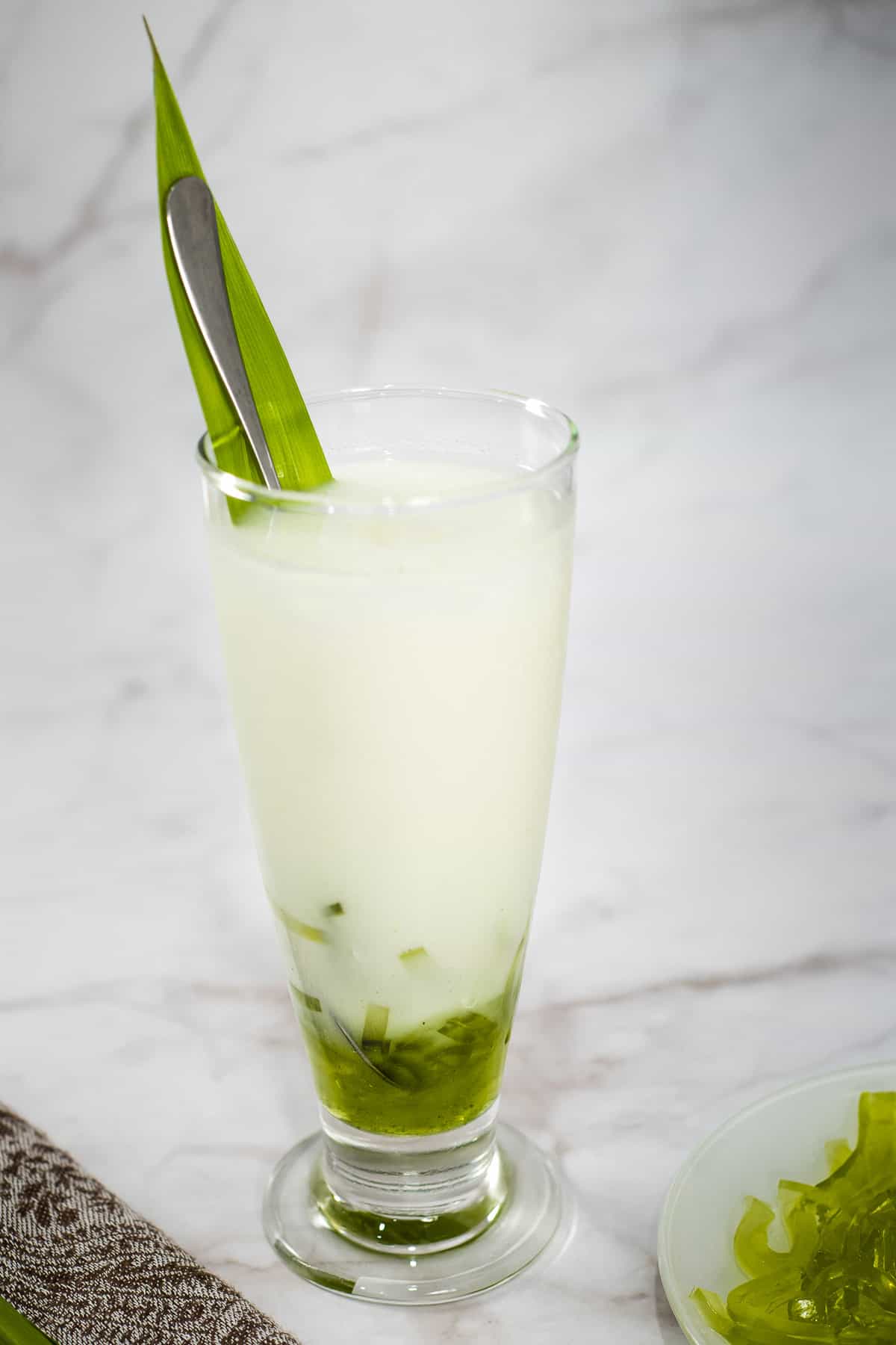 A tall glass of milk with green jelly boba strips.