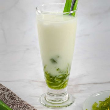 A tall glass of milk with green jelly boba strips