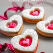 Four heart sugar cookies decorated with pink and baby pink fondant and powdered sugar.