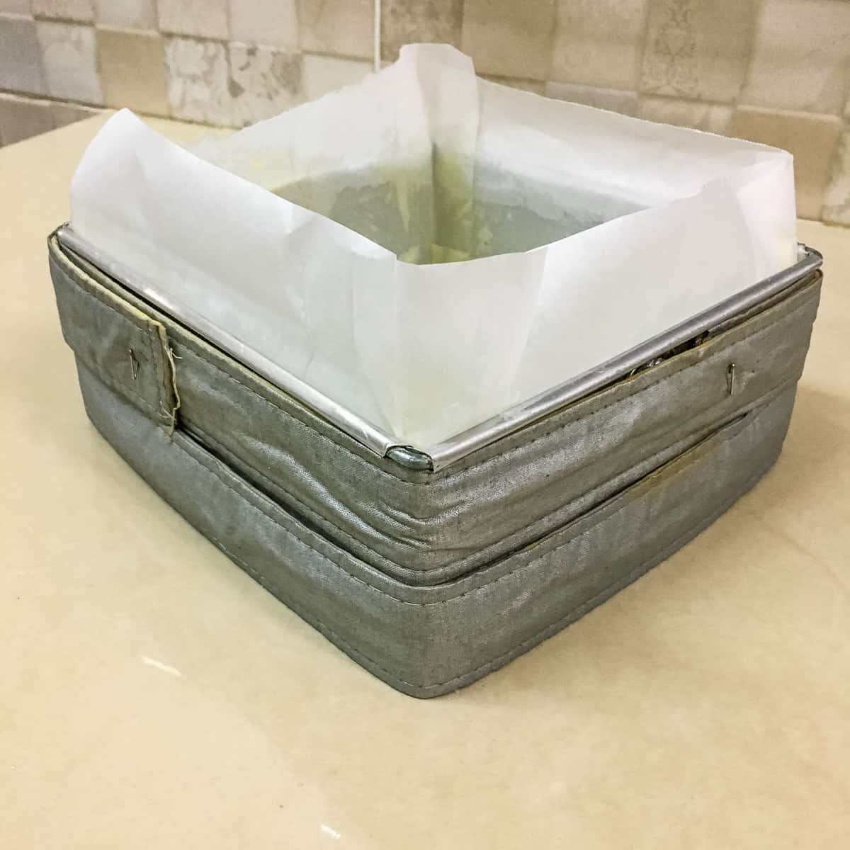 A square cake tin with parchment paper lining.