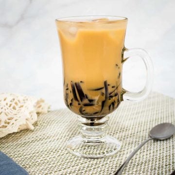 A glass of milk tea with grass jelly.