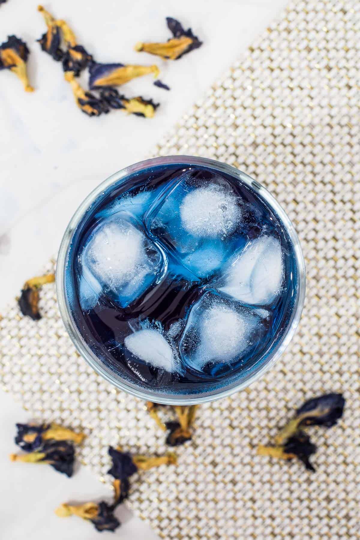 Top view of a glass of ice butterfly pea flower drink.