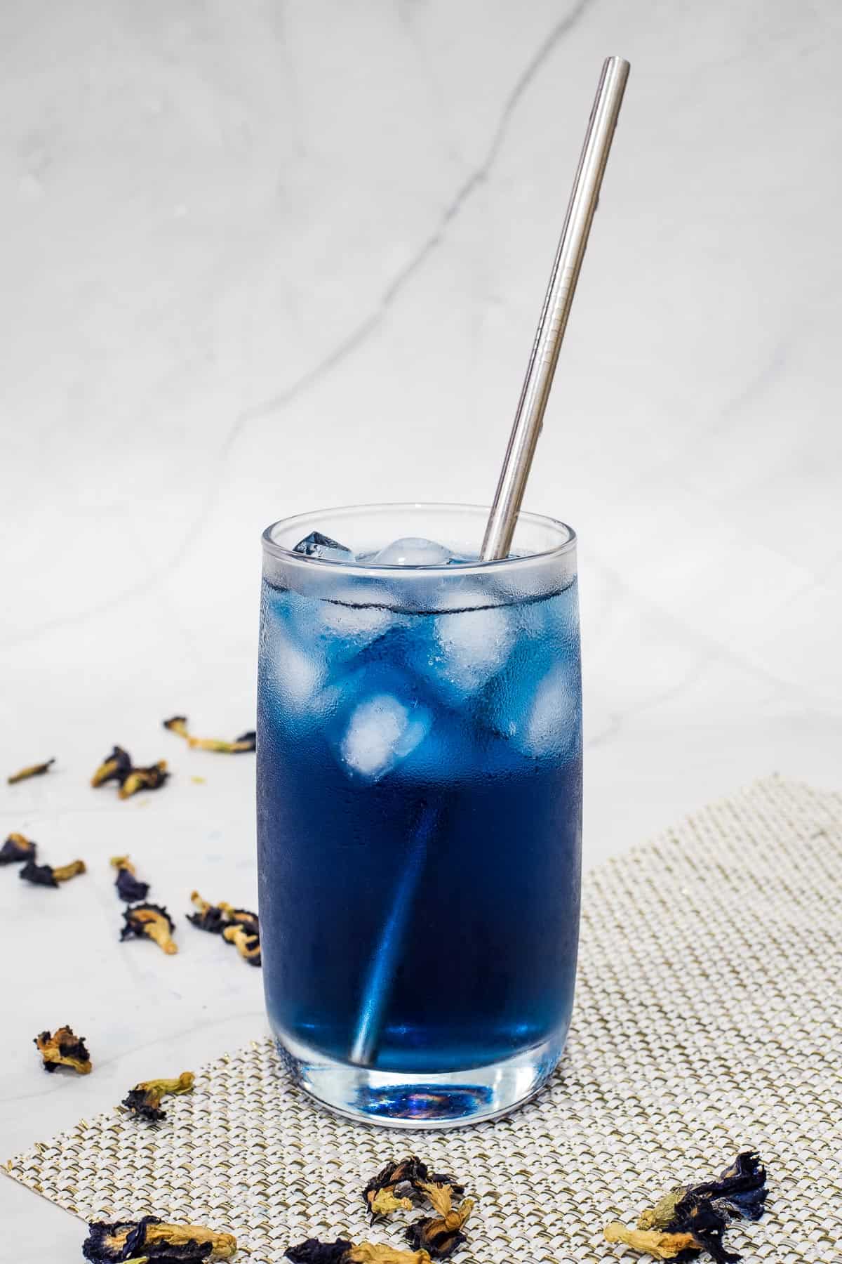 Blue ice tea in a glass with steel straw.